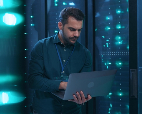 Image of a business person walking through a data center with their laptop.